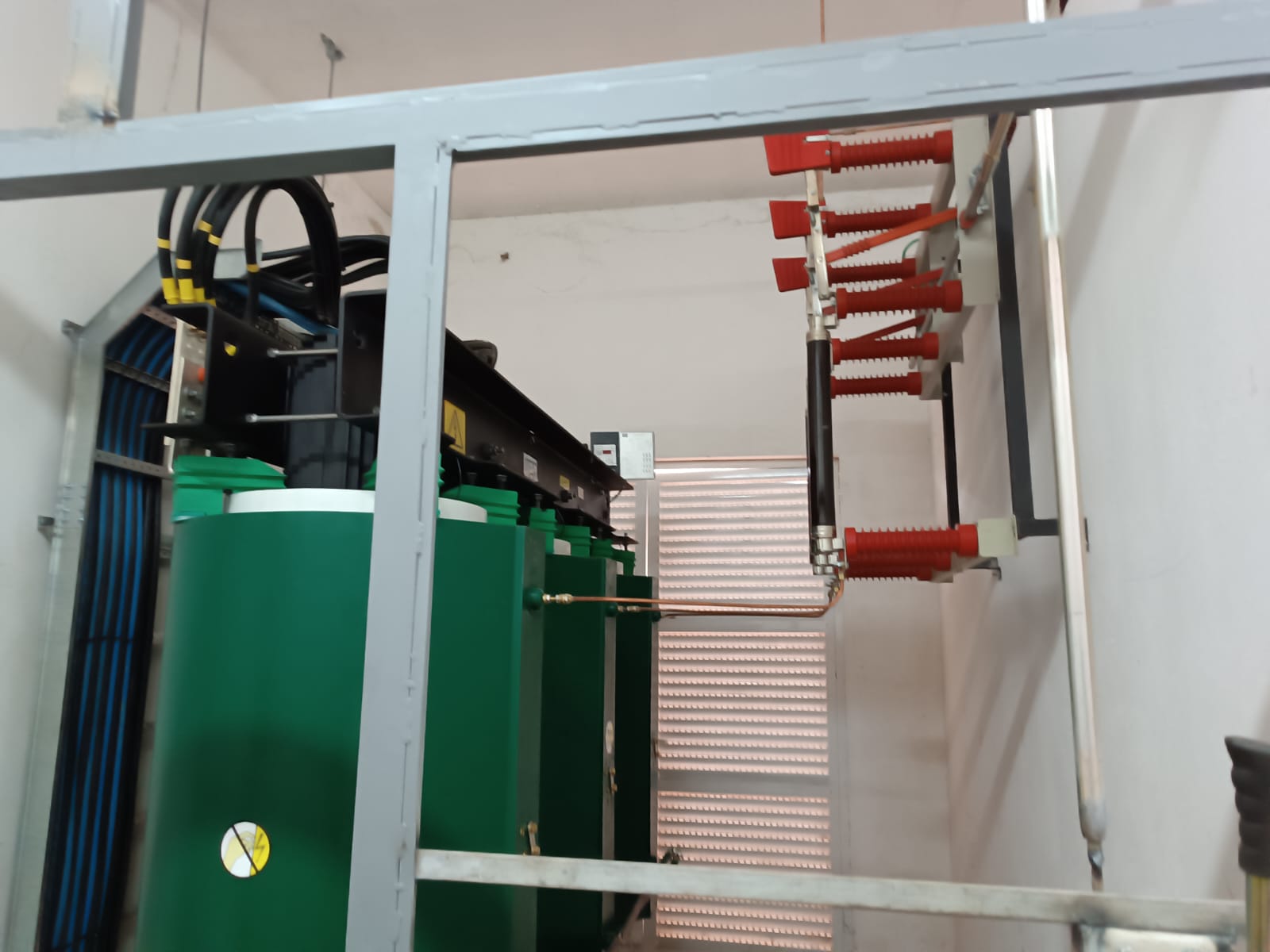 Sala técnica com transformadores, barramentos e isoladores vermelhos